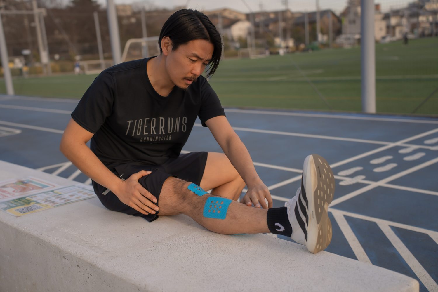 トラックに座って走ったあとのケアをする TIGERRUNS のランナー